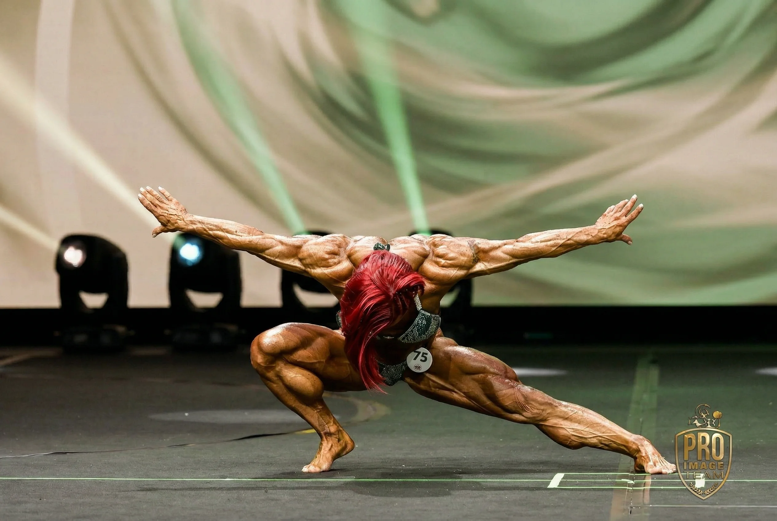 Branka Njegovec performing a dramatic wide pose at a professional bodybuilding competition